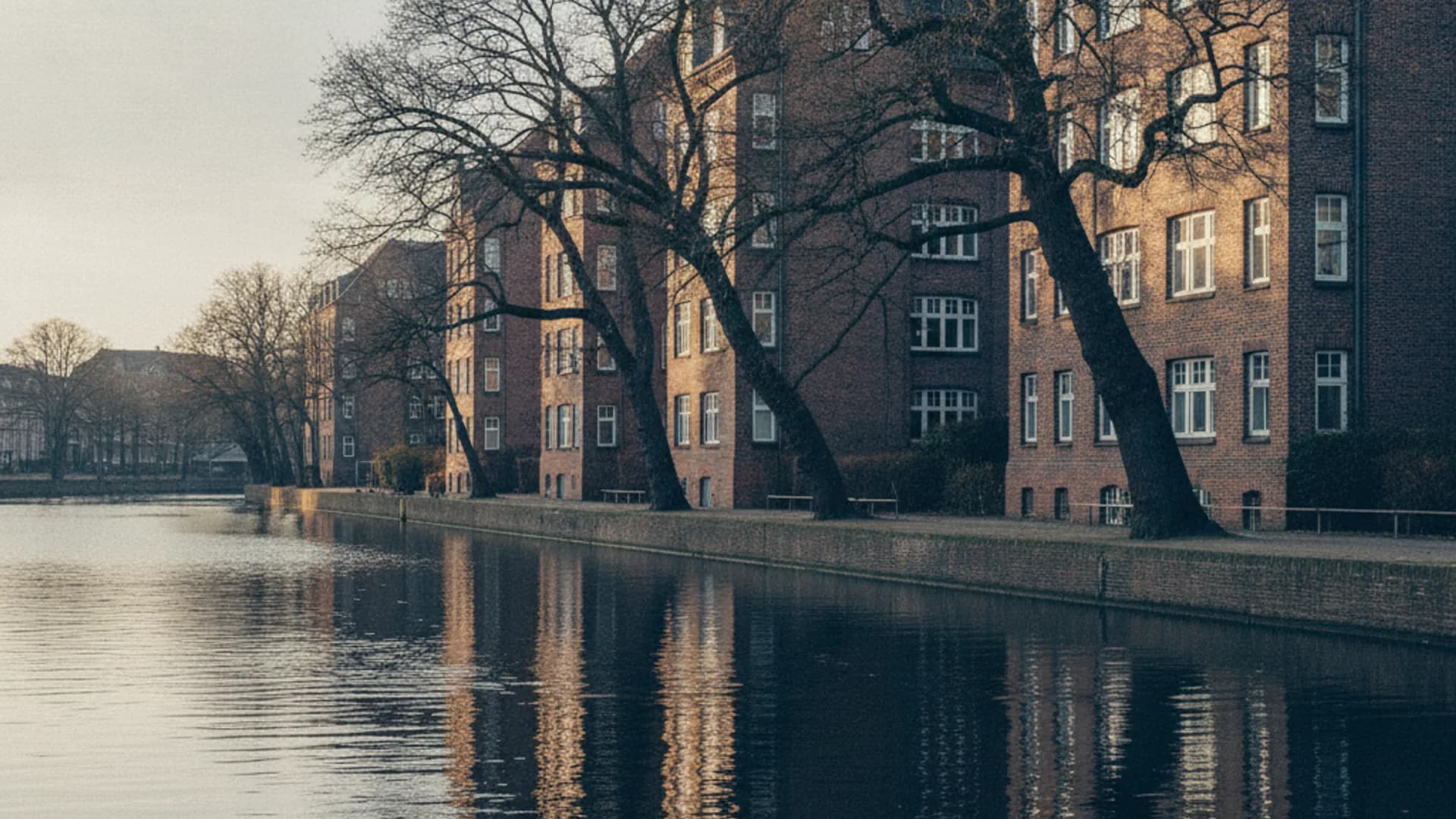 Grüner Alsterlauf mit Backsteinhäusern am Wasser in Hamburg-Alsterdorf
