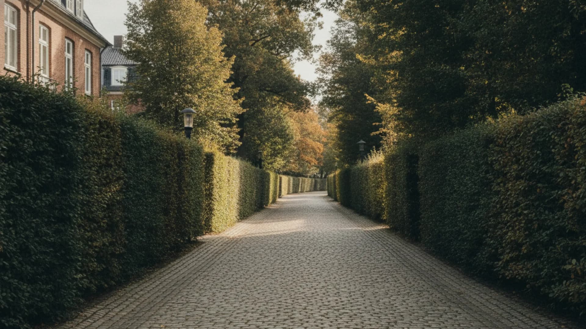 Siedlungsstraße mit Hecken und Gärten unter hohen Bäumen in Hamburg-Iserbrook